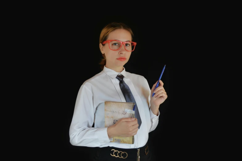 girl wearing glasses holding an open book with pen in her hand
