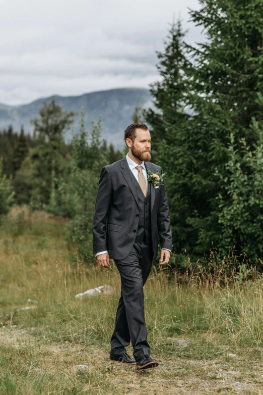 a man in a suit is walking in the grass