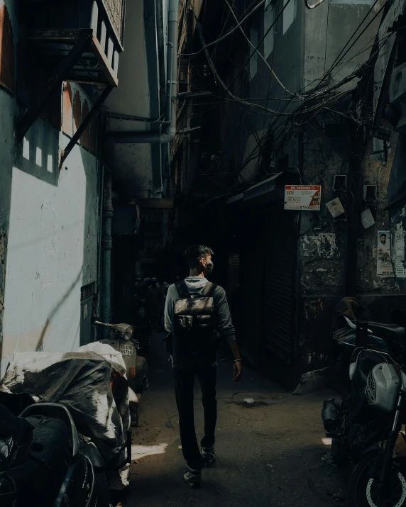 a man with a backpack walks in an alley between buildings