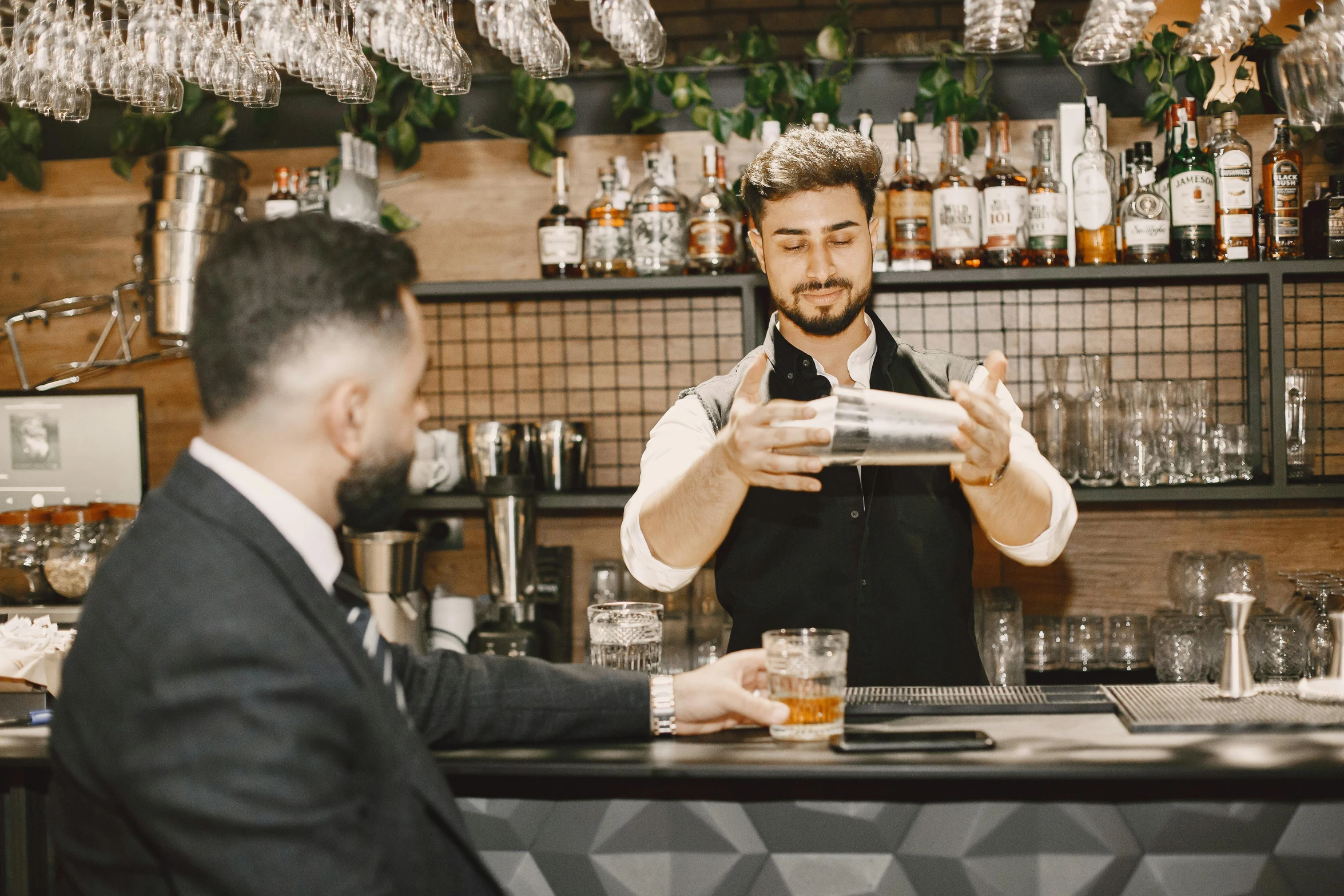 a bartender pouring a drink with a man in the background