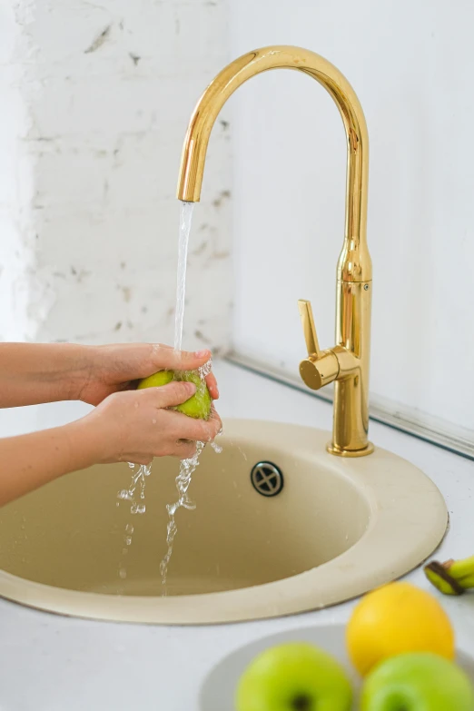 someone is washing apples in a sink with running water