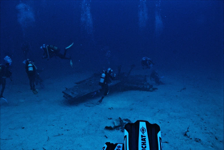 divers and divers with their gear under a boat in the ocean