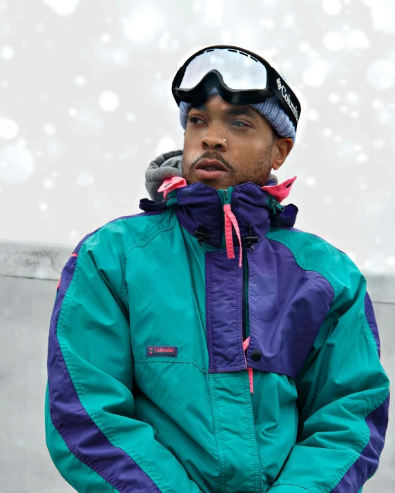 a person standing outside in the snow wearing a blue and green jacket