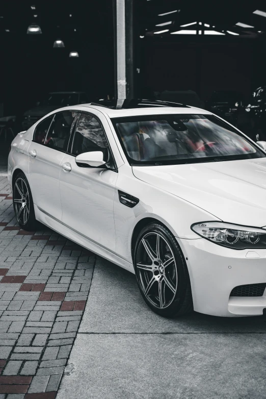 a white bmw parked on the street with brick paved ground