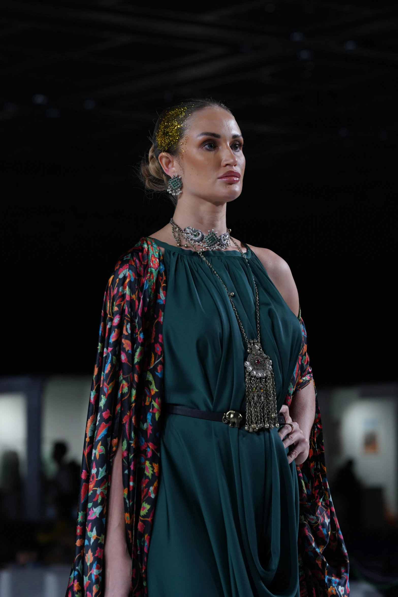 a woman in a green dress with an extravagant necklace on her neck