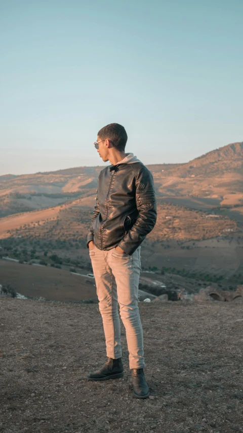 young man in all brown standing on top of a hill