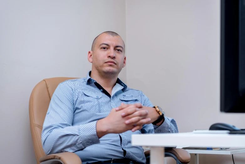 man sitting at desk in front of a computer with laptop on desk