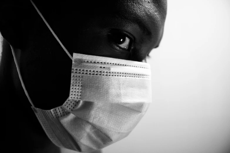 black woman in white face mask against wall