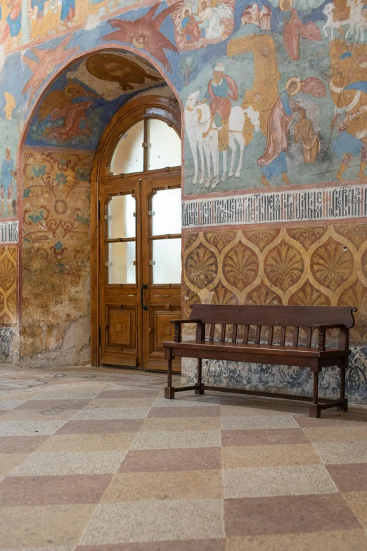 a bench and entryway to a building that has a lot of paintings