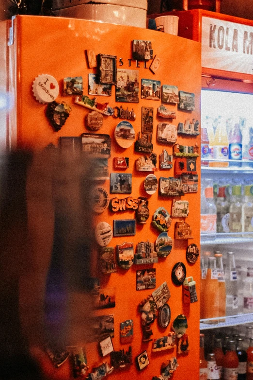 an orange refrigerator covered in many different magnets