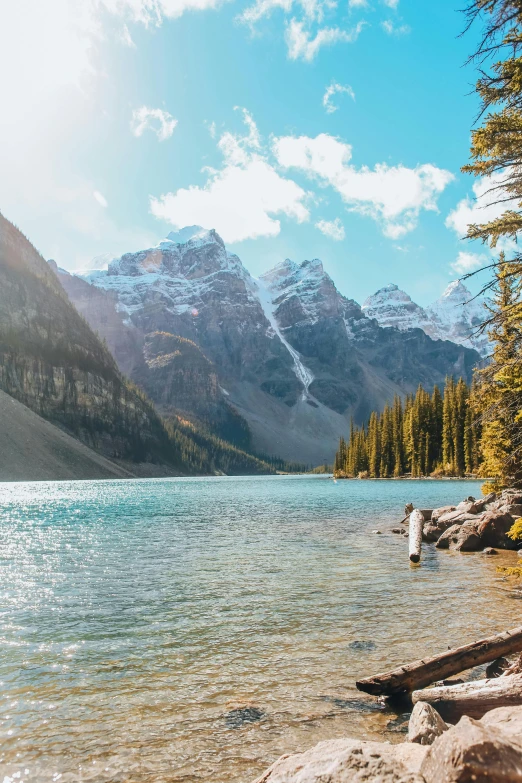 a beautiful mountain scene with people standing on a rock near water