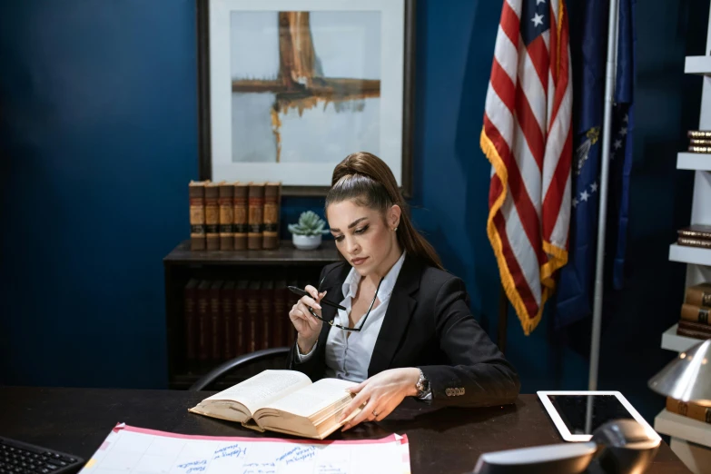 a woman sitting at a desk reading a book