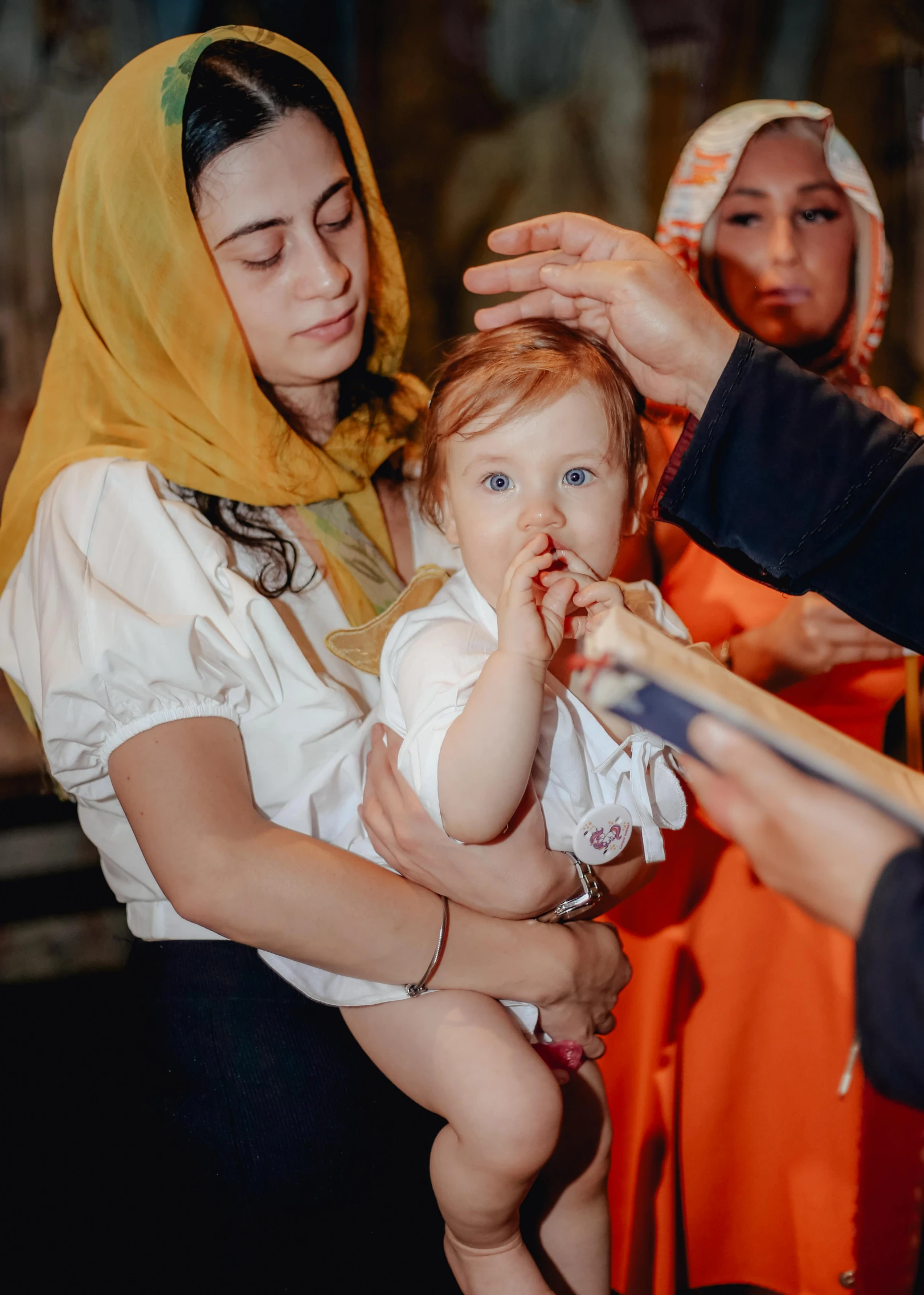 an adorable baby in a sling sitting in her mother's lap