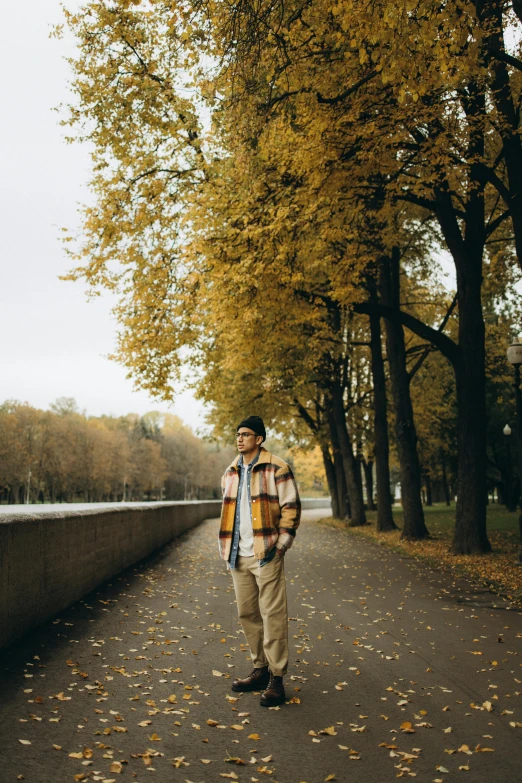 a man in plaid shirt and hat walking down a sidewalk