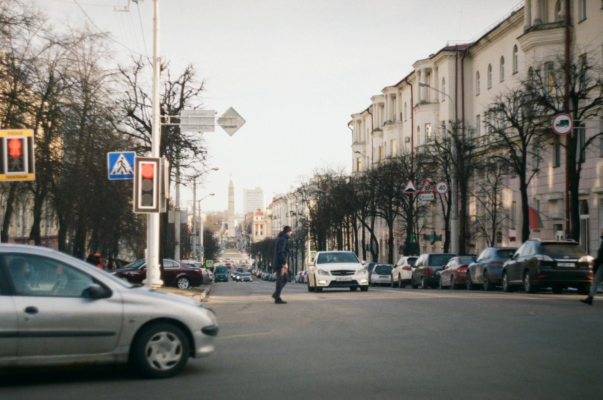 a person walking across a cross walk in the middle of a city