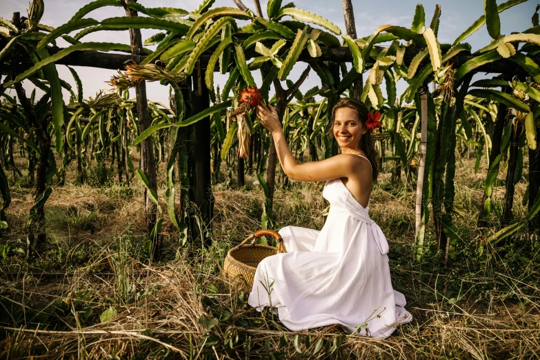 a woman sitting on the ground holding up a banana tree