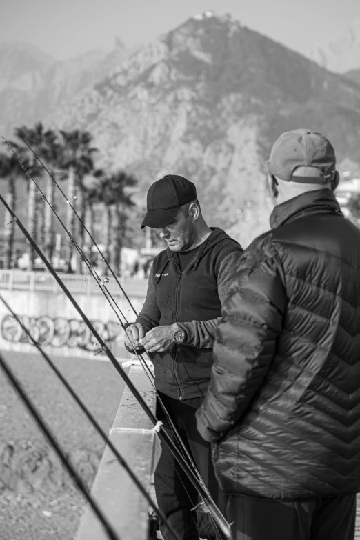 two men with skis and poles look at the water