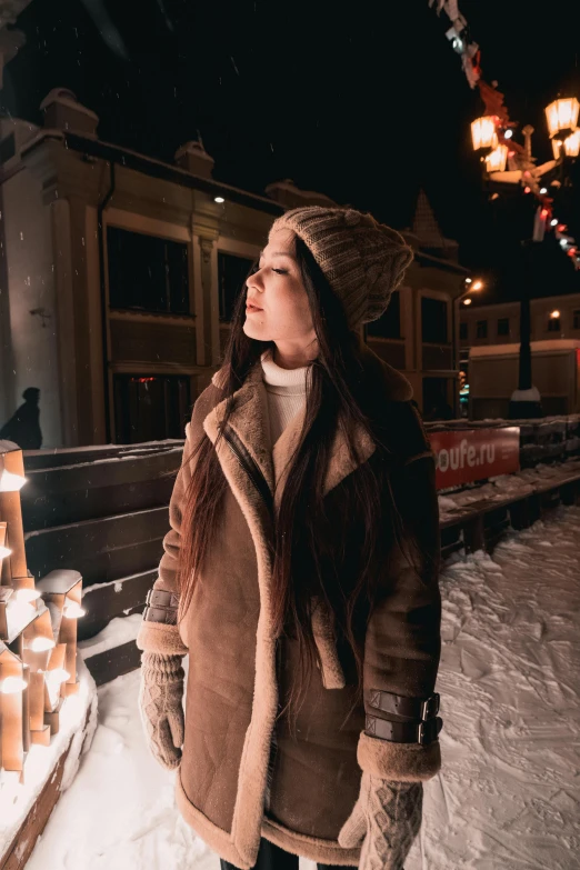 woman looking up while standing in front of a building at night