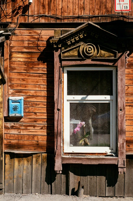 a wooden building with an open window and flowers growing outside