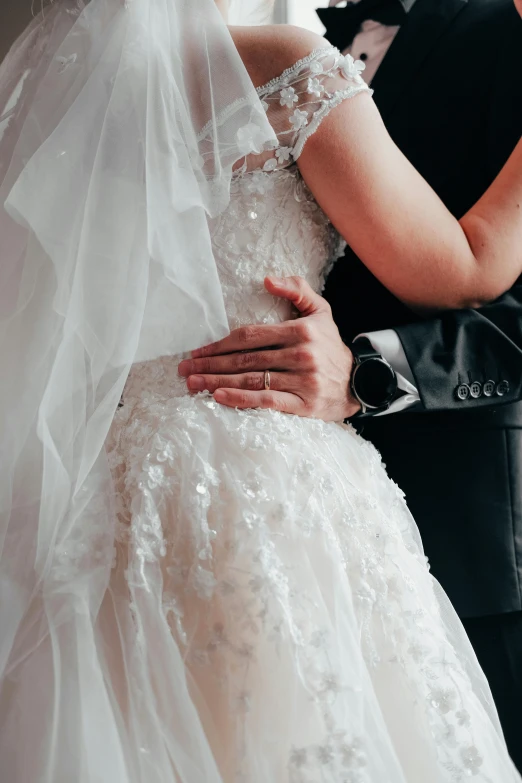 a woman in wedding dress hugging a man