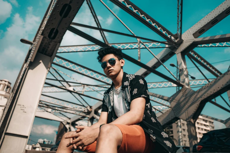 a young man sitting on top of a metal bridge