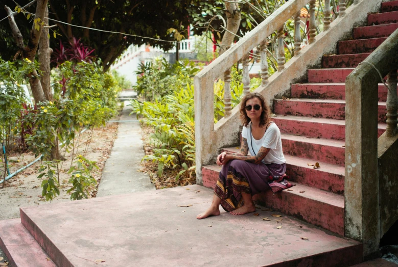 a woman sitting on a set of steps near some trees