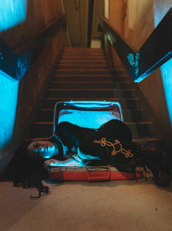 a suitcase and a girl lying in the middle of an stairs