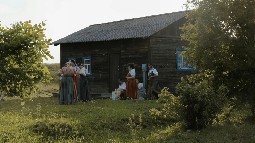 the four people are talking outside of the old house