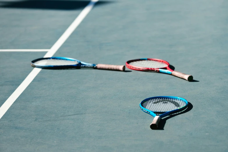 a tennis racket laying on the court, with one of its handles broken