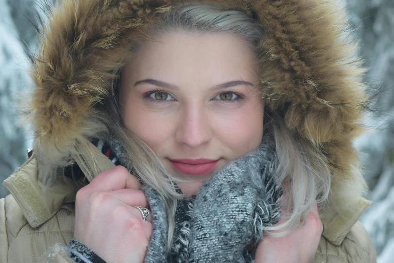 a woman in the snow with a furry hood on