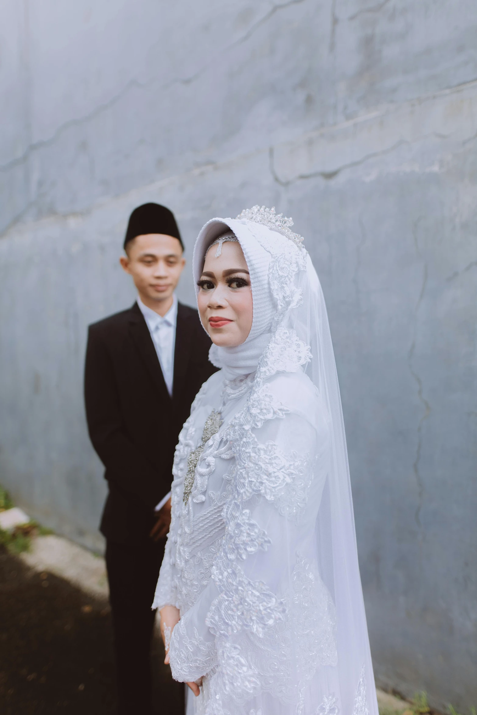 a couple posing for a pograph while dressed in wedding attire