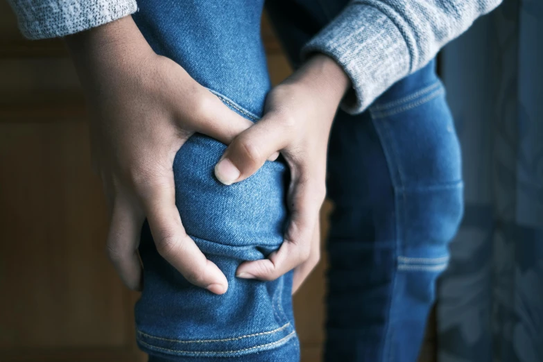 a pair of hands hold a jeans leg