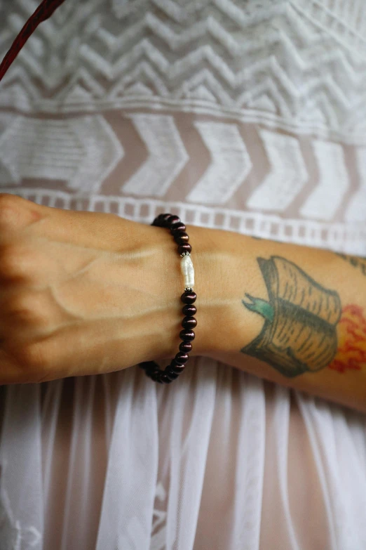 woman with tattooed arm and wrist and tattoos holding onto red string