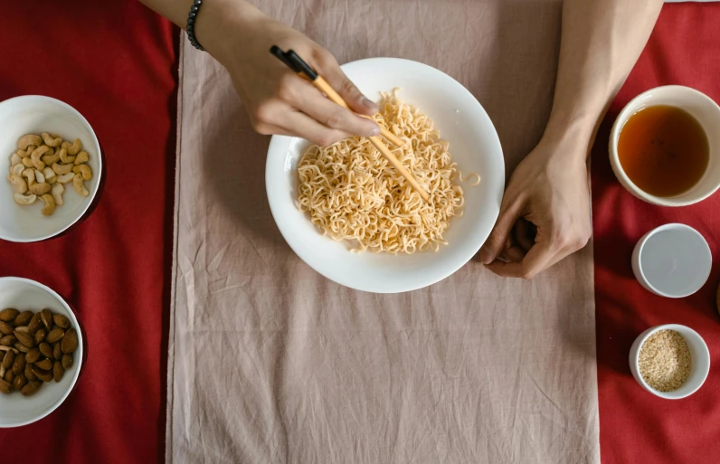 a person is holding a fork above a bowl of noodles