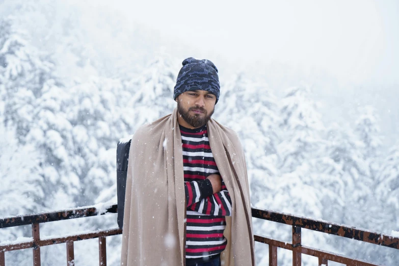 man in winter outfit standing on a deck looking at the camera