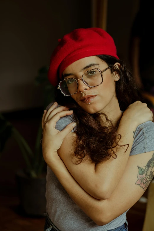 a woman wearing glasses and a red beanie with her arms folded