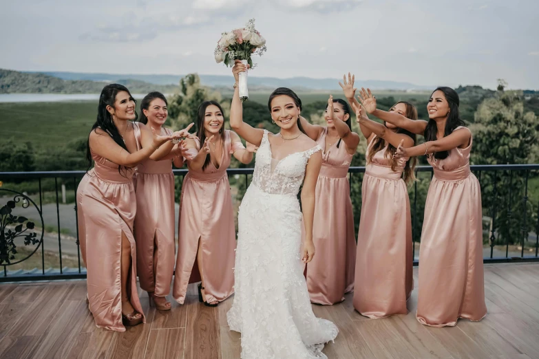 bride and bridesmaids with bouquet standing on deck holding their bouquet in the air