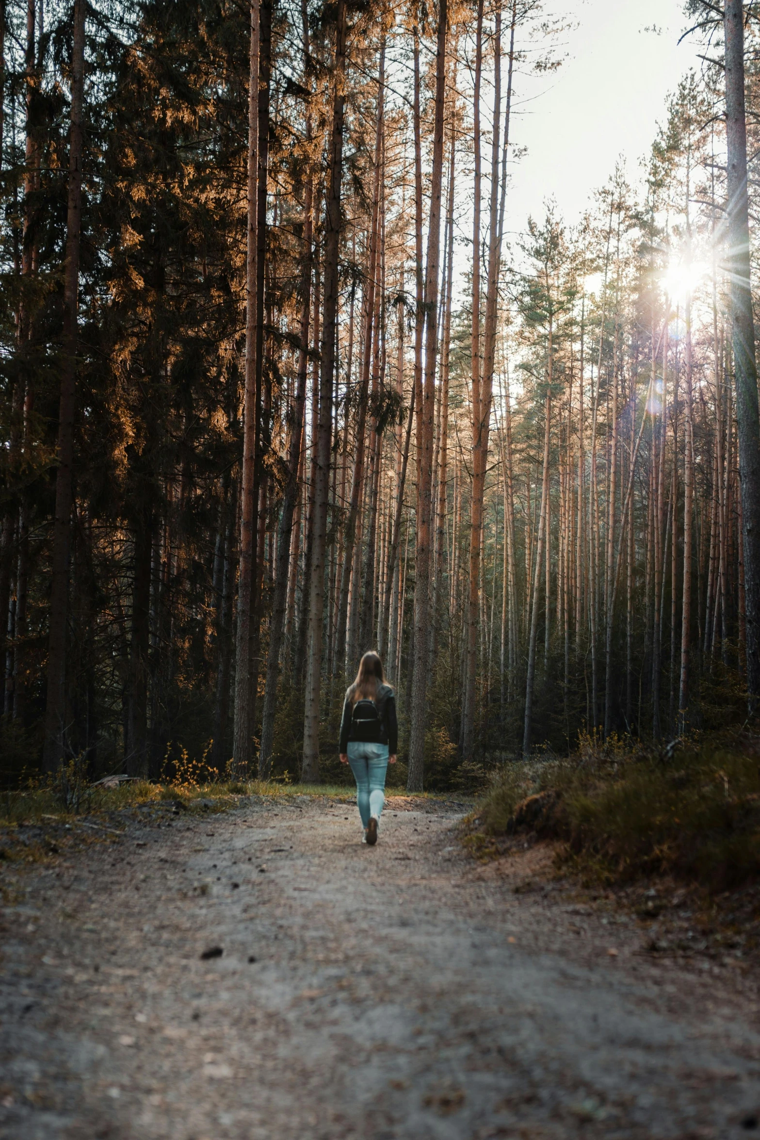 a woman walking down a wooded path through the woods
