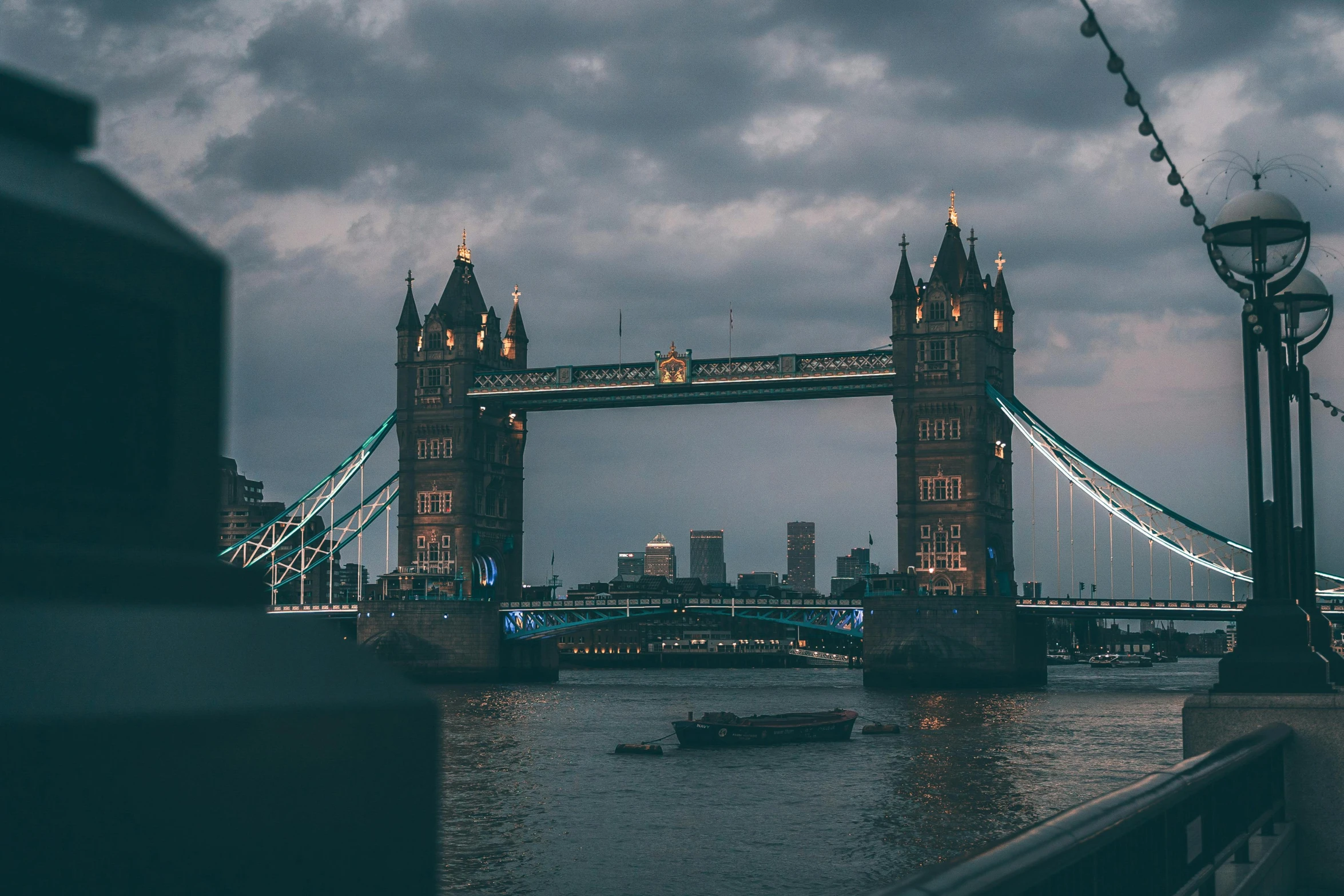 a po taken from across the water shows a bridge with a tower that is surrounded by lights