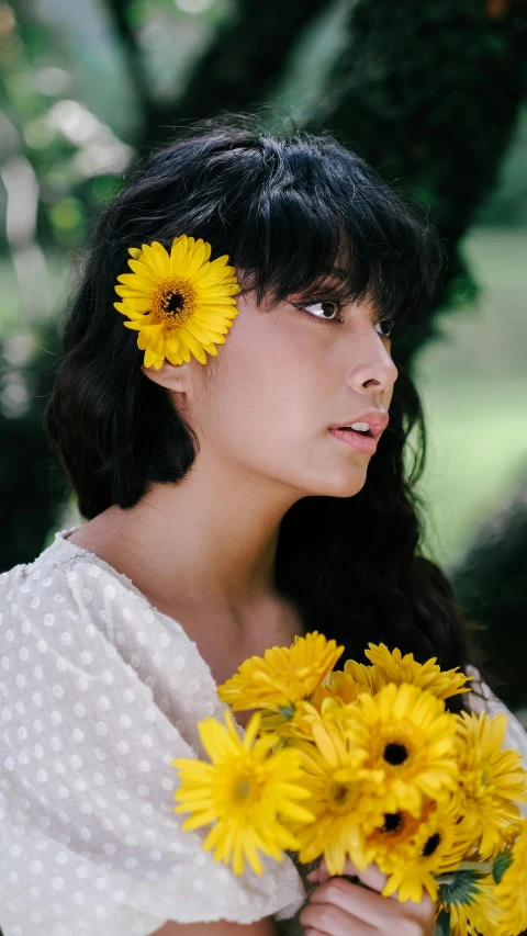 a woman wearing a dress holding a bouquet of sunflowers