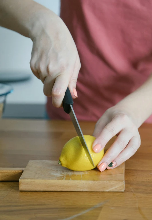 a woman  up an orange on a wooden counter top