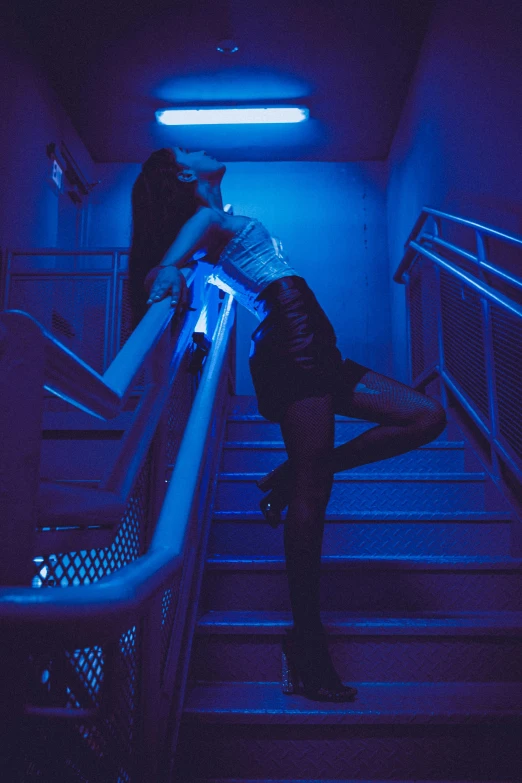 a woman is sitting on some stairs in a dark room