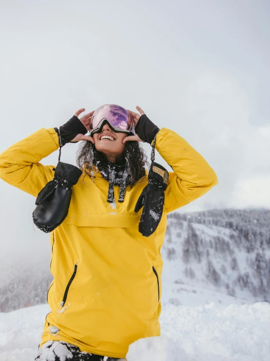 a young woman standing on top of a snow covered mountain