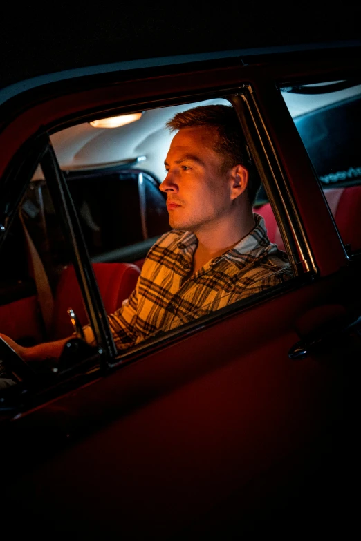 a man in the drivers seat of a car looking out the window