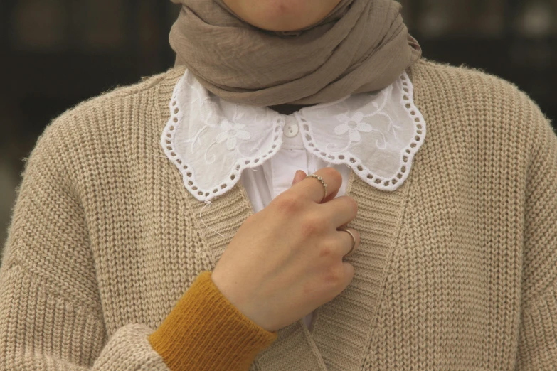a woman with a white collar shirt and sweater on