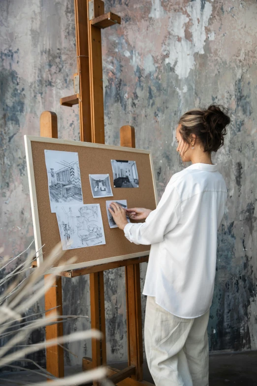 a woman with a pen is writing on the floor by a easel