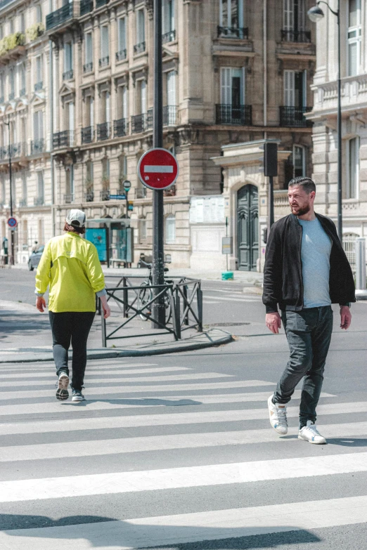 two people walking across a crosswalk at a street intersection