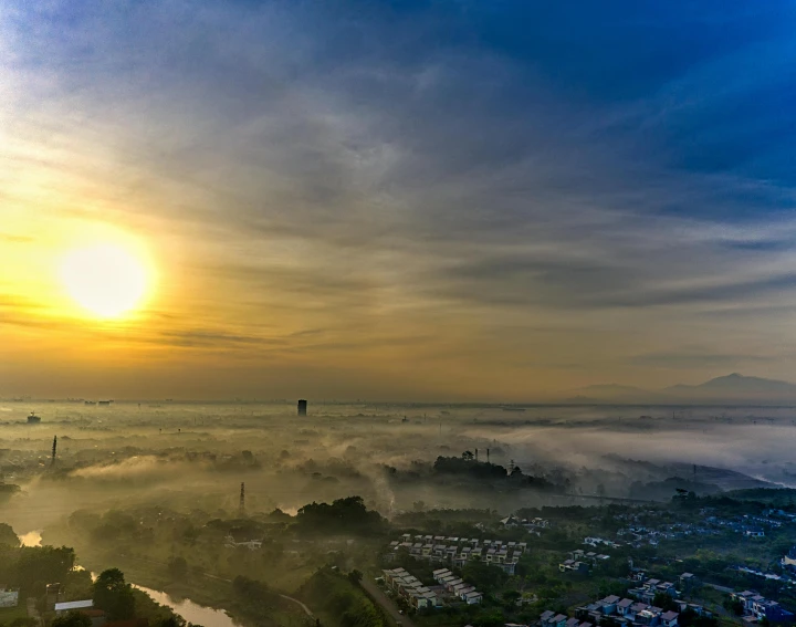 there is a large sun that is setting on a foggy day