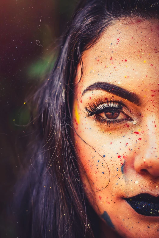 a woman's face with black lipstick and glitters around her eyes