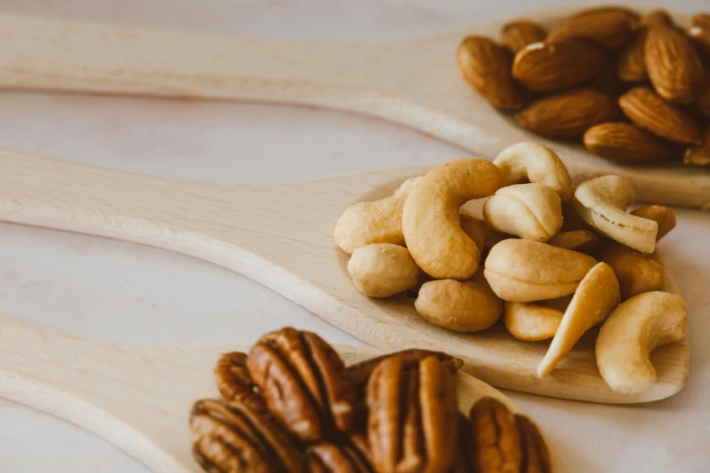 closeup of walnuts, almonds and pistachio nuts on spoons